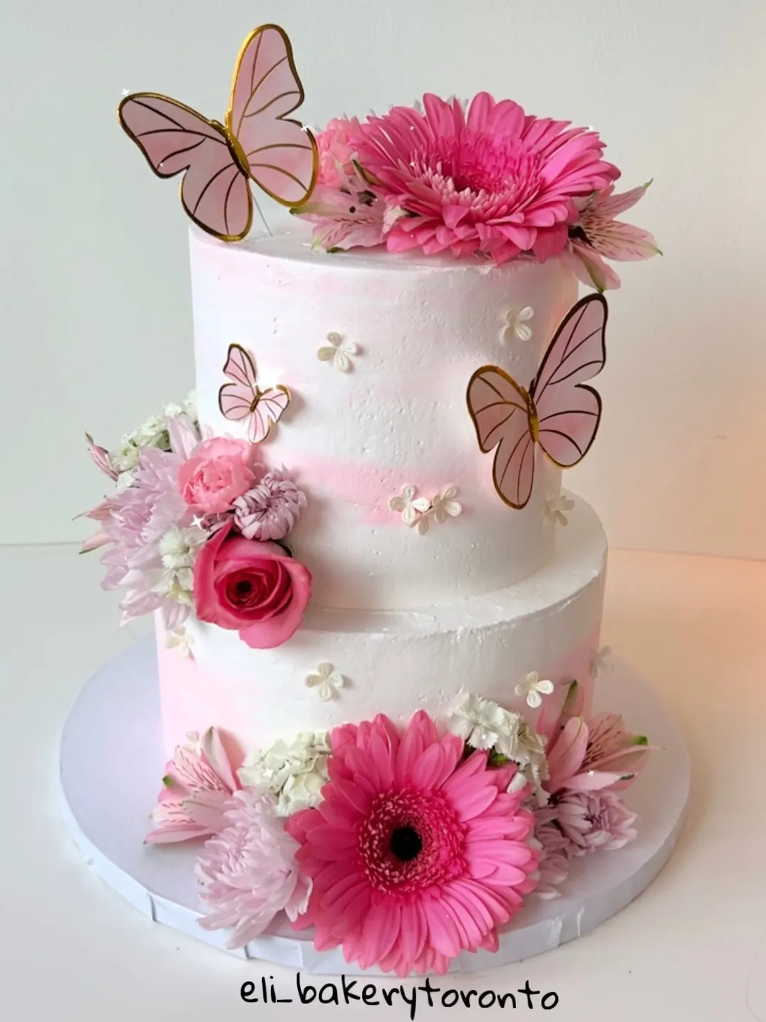 Two-tier pink floral cake with butterflies by Eli Bakery Toronto
